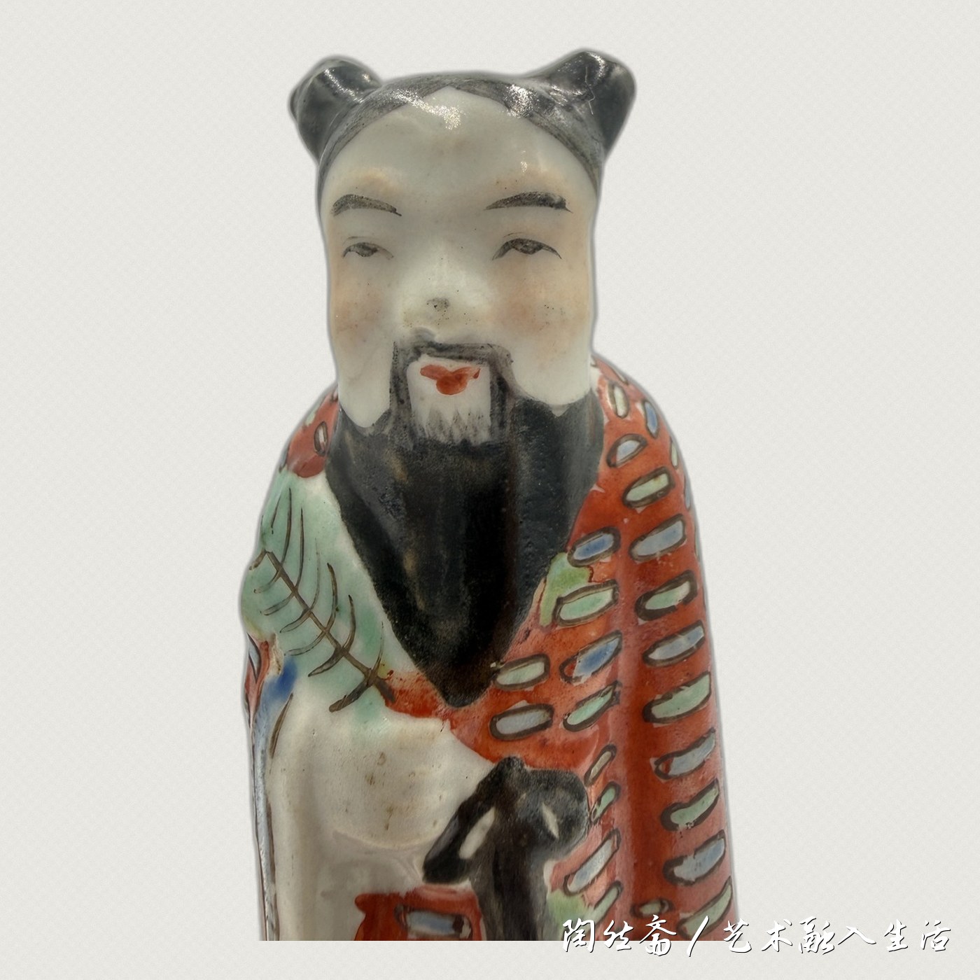 汉钟离造像面部特写，笑眼、黑须、红唇、黑幞头